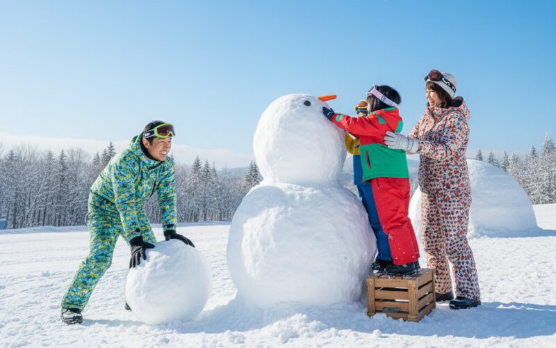 北海道の雪遊び場で雪だるまを作る子連れ家族