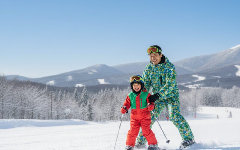 北海道のスキー場で笑顔で滑る親子